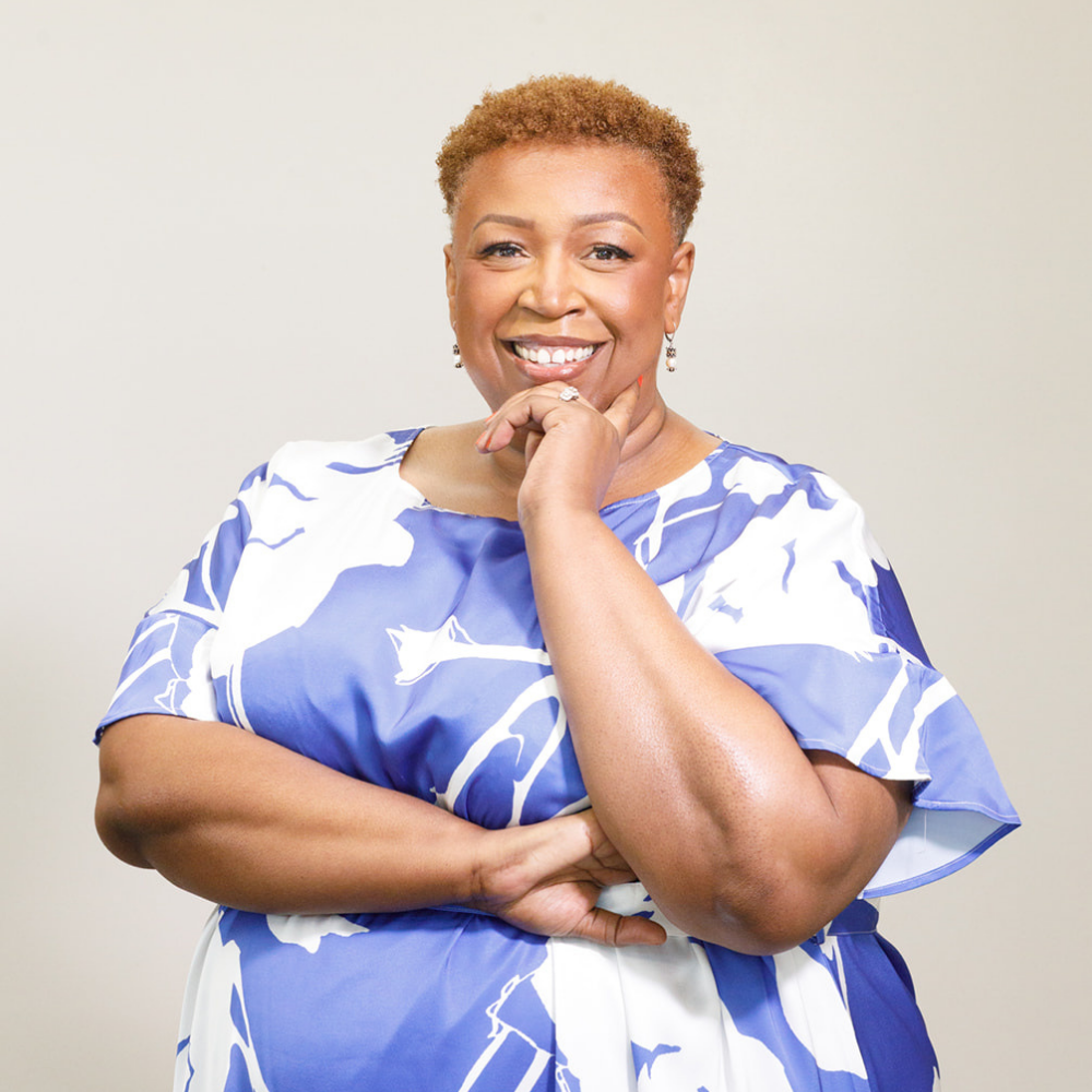 Tessa Tubbs smiling with arms crossed in a blue and white print top